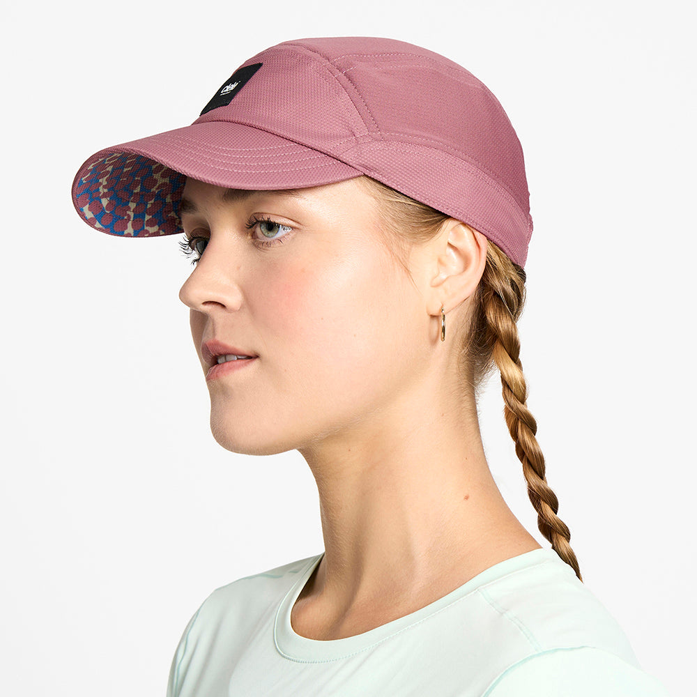 side view of the ciele athletics FTSCap unisex running hat with a curved brim in deco rose color, on a model